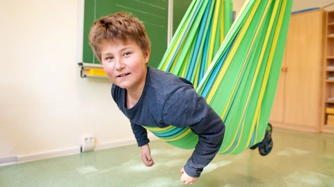  Ein Schüler schaukelt in einem farbenfrohen Schwungtuch.