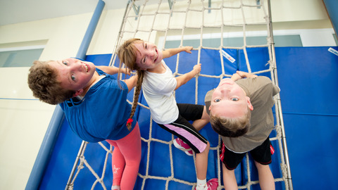 3 Schüler im Sportunterricht an der Kletterwand