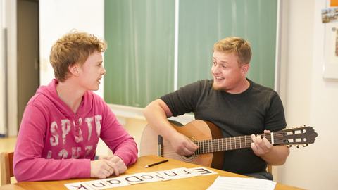 Zwei Personen mit Gitarre beim Musizieren und Singen