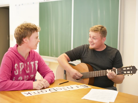 Zwei Personen mit Gitarre beim Musizieren und Singen