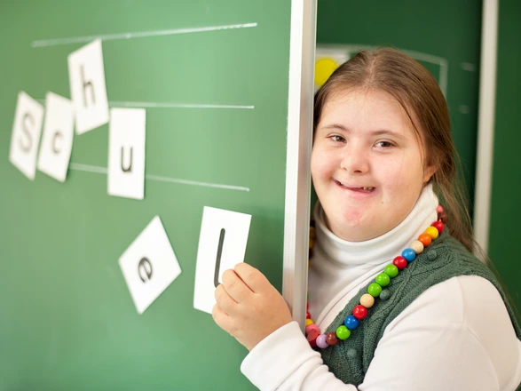 Eine Schülerin steht lächelnd an der Tafel.