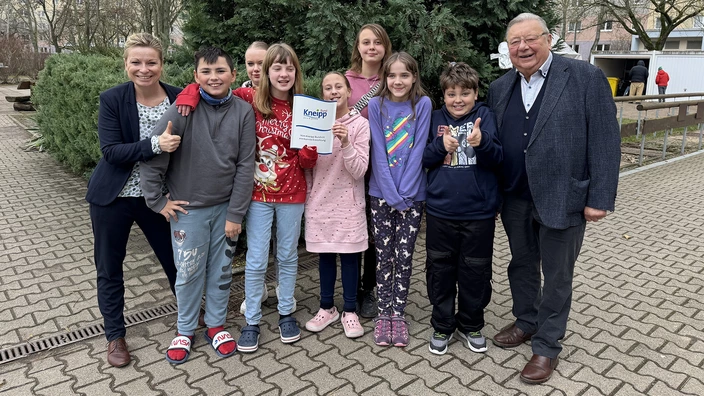 Schulleiterin Dr. Katja Kirchner, eine Schülergruppe und Dr. Sigurd Scholze präsentieren stolz das neu erhaltene Kneipp-Zertifikat.