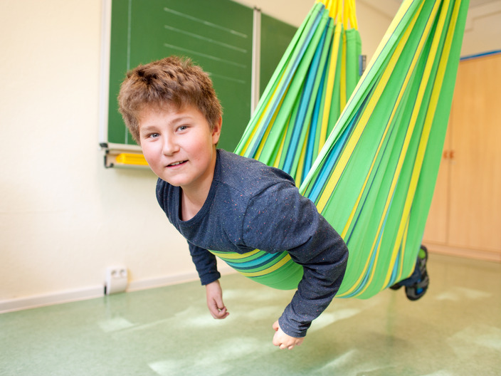 Ein Schüler schaukelt in einem farbenfrohen Schwungtuch.